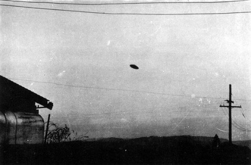Black-and-white McMinnville photograph showing a disc-shaped object in the daytime sky above a farm